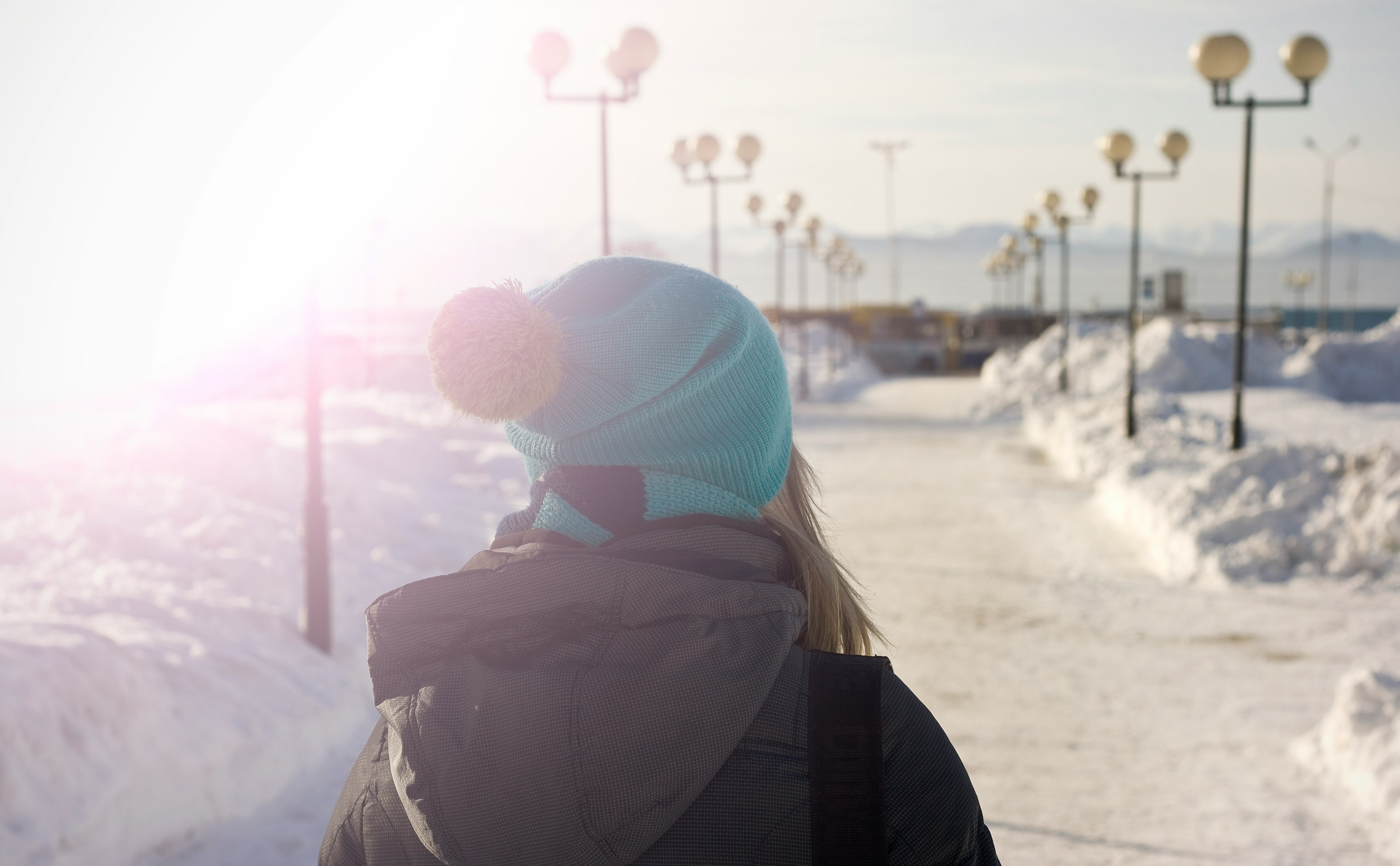 woman walking in snow-covered pathway during day